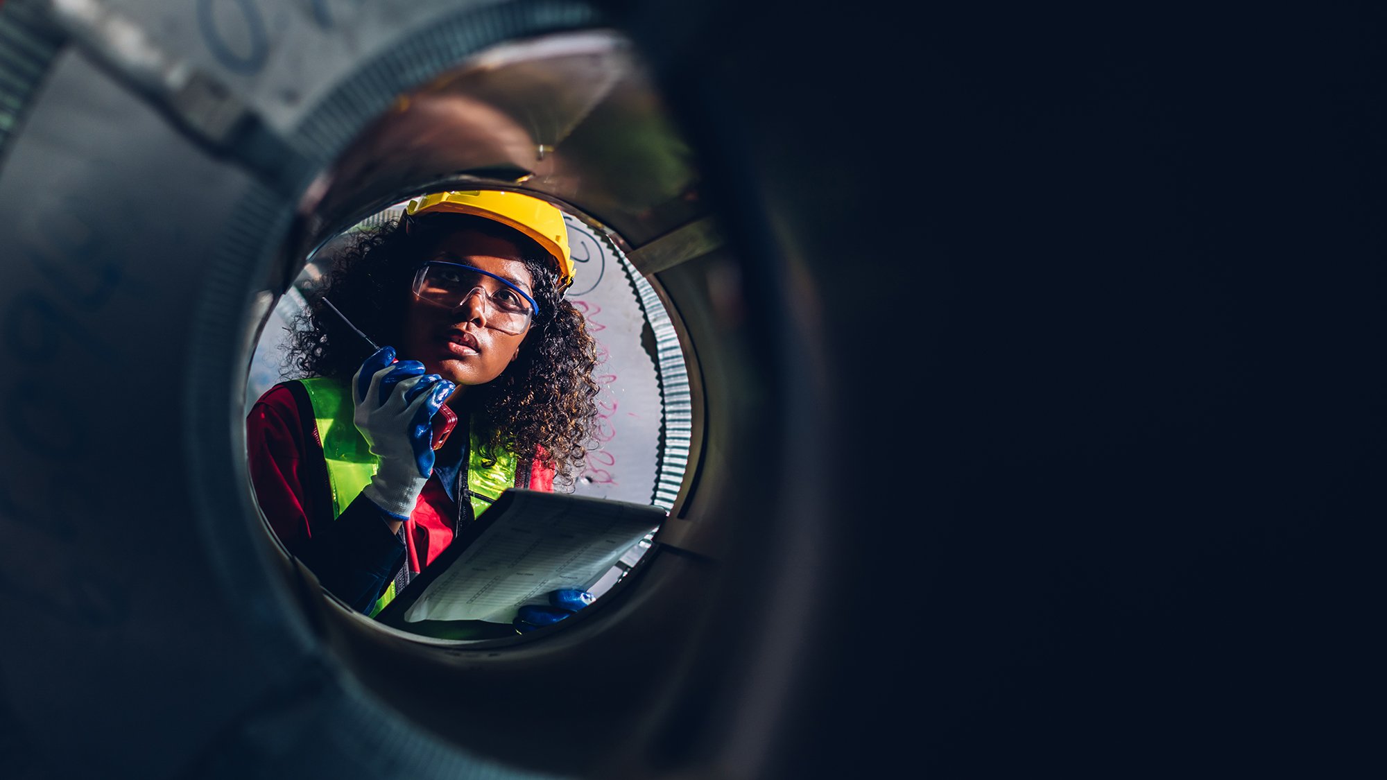 Looking ahead to safety dates for 2025 - image of female construction worker through pipe
