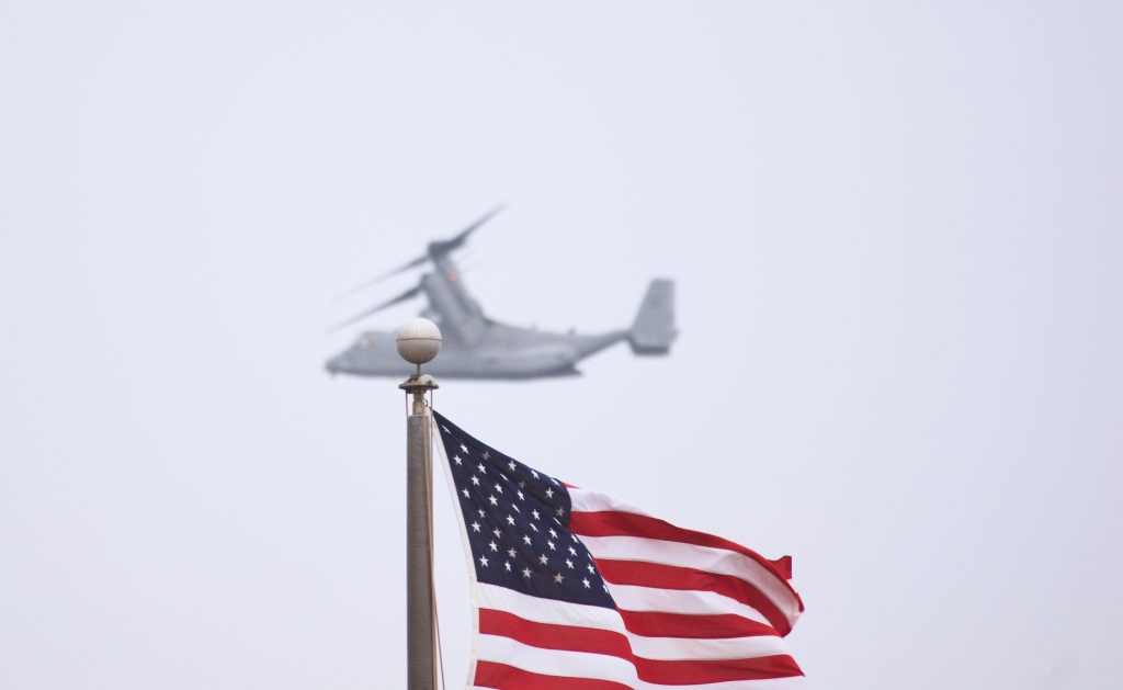 BAE Systems Marine Osprey flying behind US American Flag